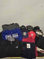 All items laid out together: jackets, shirts, pants, caps