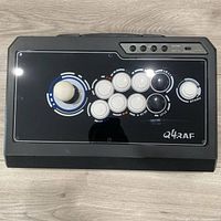 Top view showing joystick, eight action buttons, branding