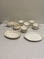 Group view showing all ten pieces: six teacups, creamer, covered sugar, round plate, oval plate