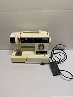 Full view of Singer sewing machine with foot pedal and cord