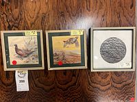 Three framed artworks side by side on wood wall