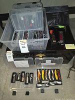 Lot overview showing two clear storage boxes and trays with multiple corkscrews and bar tools
