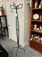 Full view of black metal coat rack next to shelving