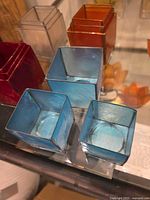 Close-up of blue, amber, red, and clear square glass candle holders