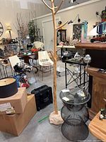 Overall lot showing wooden coat tree, steel wire table, surrounding context