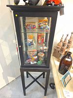 Front view of one cabinet showing glass door, shelves, and stand