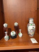 Group view showing all six porcelain vases and three stands on shelf