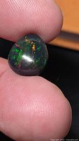 Close-up of teardrop cabochon black opal showing multicolored play-of-color