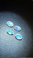 Four oval opals showing play-of-color on dark background