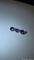 Three round blue-purple faceted stones on light background