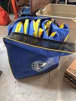 Blue zippered carry bag containing stacked PFDs