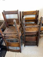 Four stacked wooden chairs showing backs and legs