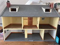 Front view of dollhouse showing exterior, interior layout, dormers and chimneys