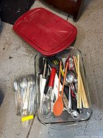 Overview of baking dish with lid, bagged cutlery and utensils