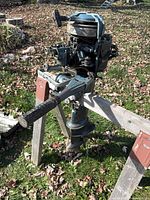 Port side view of complete outboard motor on stand showing tiller, powerhead, driveshaft housing and propeller