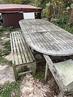 Top view of weathered teak oval extension table with one bench alongside