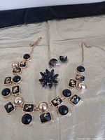 Necklace, brooch and earrings on gold cloth, full lot view