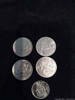 Five coins on black background: four Voyageur dollars, one 50-cent jubilee