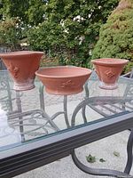 All three terracotta pots on glass table showing shapes and patina