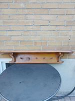 Front view of full wooden wall shelf with five pegs