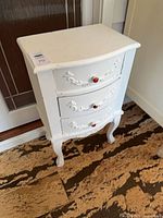 Front and side view of white three-drawer chest showing curved front, cabriole legs, red knob pulls