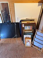 Portfolio case, easel, stack of picture frames and wooden rack