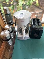 Group shot showing coffee maker, toaster, thermos and two containers