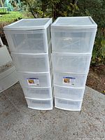 Two identical white plastic storage drawer towers side by side outdoors