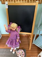 Easel front with chalkboard surface; doll posed in front
