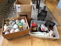 Overview of lot showing boxes with light bulbs, candles, accessories and outdoor lantern