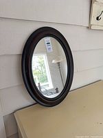 Full view of oval wall mirror leaning against wall