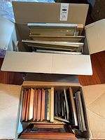 Two cartons filled with assorted frames of varying sizes and finishes