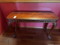 Full view of carved wood sofa table against wall showing cabriole legs and apron detail