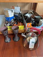 Overview showing stainless kettle, goblets, box of assorted teapots, cups and French press