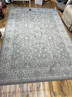Full view of gray oriental floral area rug on wood floor