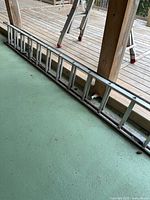 Full ladder collapsed on green floor, showing overall length and two-section construction