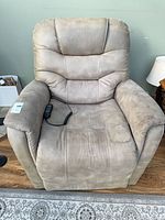 Front view of beige microfiber power lift recliner with remote on seat