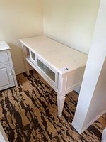Front angle view of white console table showing glass panels and legs