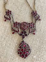 Close-up of pendant and side motifs showing red stones and metal detail