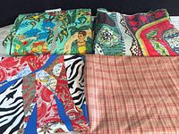 Four folded fabrics including Frida print, green patterned, red abstract, plaid