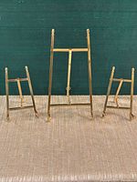 Front view of three brass easel stands upright