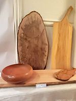 Front view showing oval live edge board, bottle-shape board, rectangular board base, and round bowl