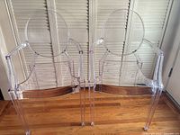 Front view of two clear acrylic ghost chairs with oval backs