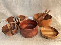 Group shot of five wooden bowls, two wooden servers and stainless fork