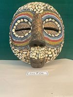 Front view of carved wood tribal mask with shell and bead decoration