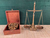 Overall lot showing brass sundial compass in open wood box beside brass balance scale