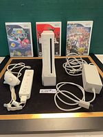 All items in lot: Wii console on stand, controllers, power adapter, three game cases