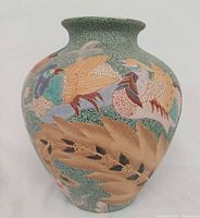 Front view of green crackle glazed vase showing two colourful birds and foliage