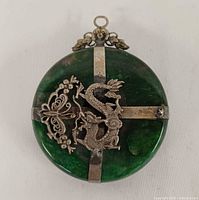 Front view showing dragon motif and silver crossband on green jadeite disc