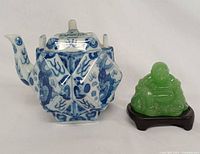 Front view of porcelain teapot and green Buddha figurine